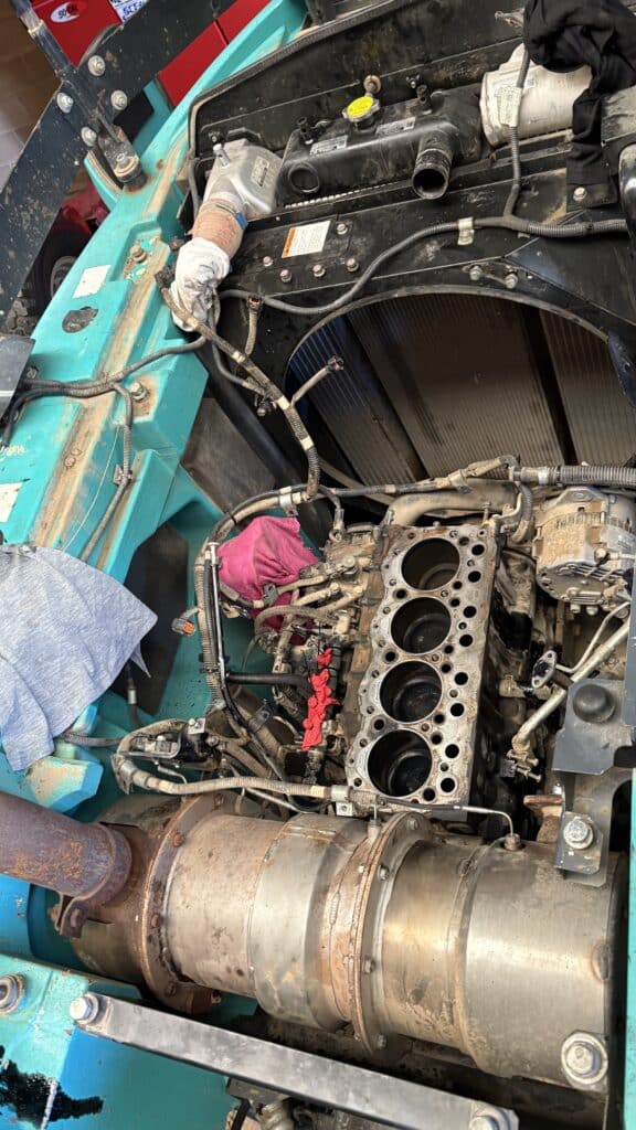A disassembled engine with exposed cylinders and various hoses and parts visible inside an industrial vehicle.